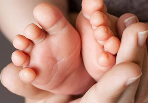 mom's hand holding cute baby feet - maternal mental health
